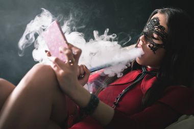 Genç, güzel kız karnaval maskesi olan bir nargile duman