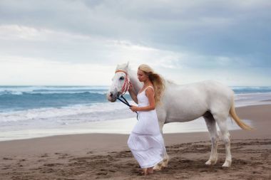 Atla sahilde yürüyen güzel genç kadın ata