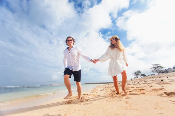 Свадебная пара только что вышла замуж держится за руки и гуляет по пляжу — стоковое фото