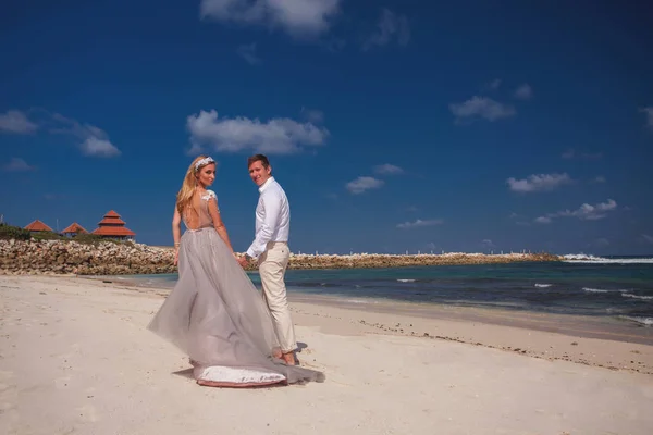Matrimonio coppia appena sposato si tiene per mano e camminare in spiaggia — Foto Stock