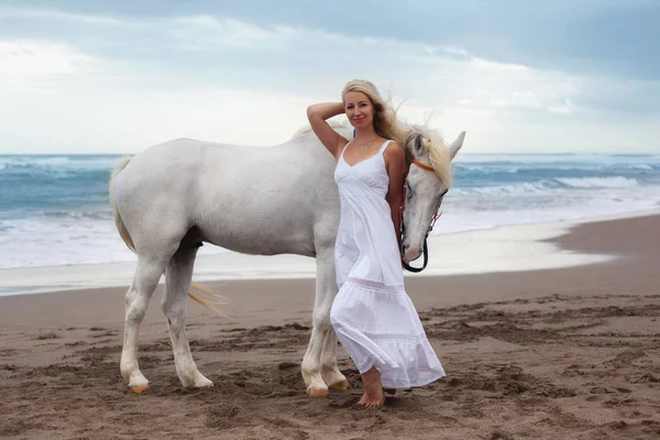 Atla sahilde yürüyen güzel genç kadın ata — Stok fotoğraf