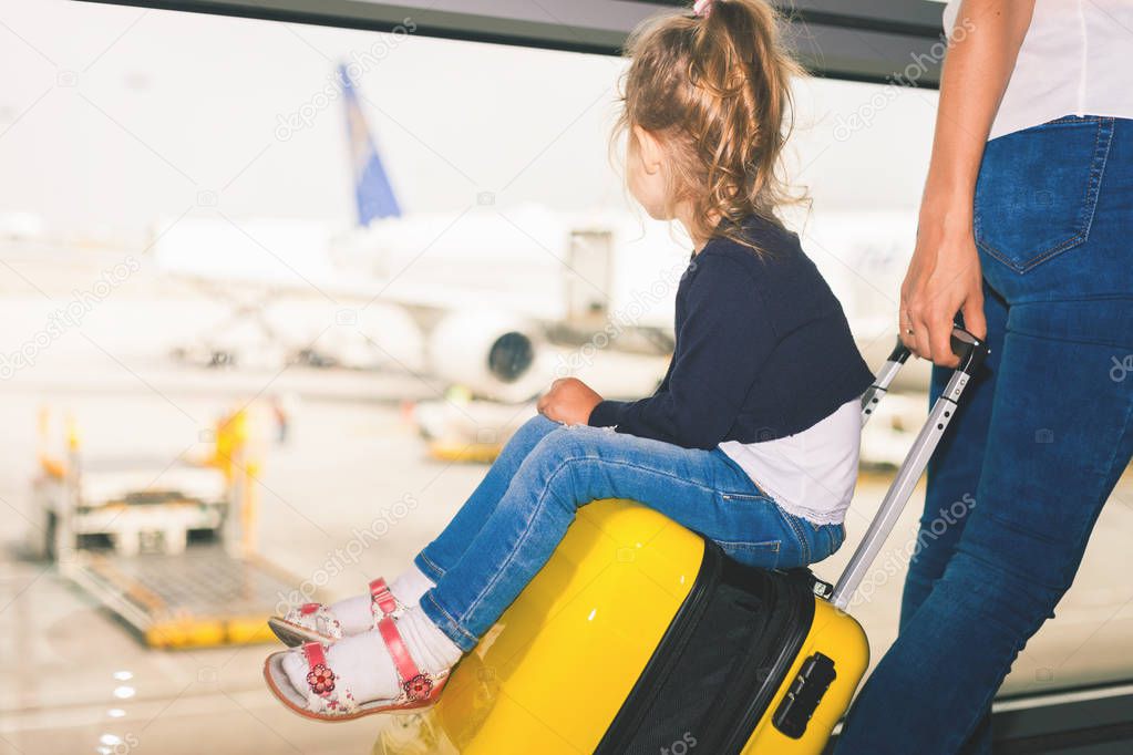 Mom carries your luggage with happy baby at airport terminal.