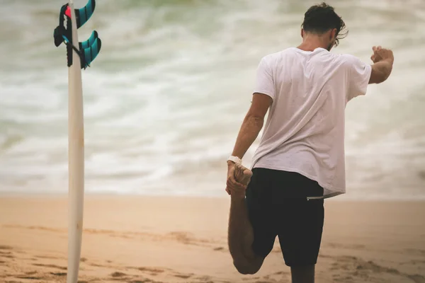 Muž surfař strečink a zahřívání před surfování — Stock fotografie