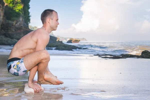 英俊的男人做瑜伽在悬崖与蔚蓝的大海背景 — 图库照片