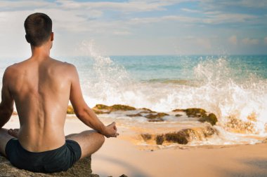 Yoga, meditasyon, Lotus pozisyonu deniz su kenarında oturan yapan erkek