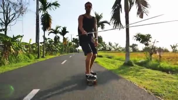 Skateboarder riding by the road near beautiful rice terraces, Bali — Stock Video