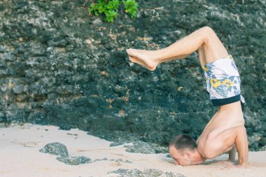 Cliff mavi deniz arka plan ile Yoga yapan yakışıklı erkek