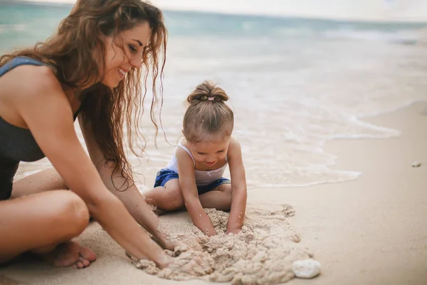 Childrens dag. Moeder en baby spelen in de buurt van strand. — Stockfoto