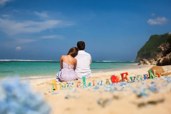 幸せなカップルの肖像画は海を見渡せるビーチに座っています。 — ストック写真