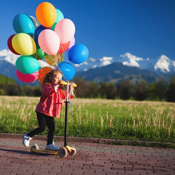 Kinderen leren om te rijden scooter in een park op zonnige zomerdag. Peuter jongen en meisje in veiligheidshelm rijden een roller. Kinderen spelen buiten met scooters. Actieve recreatie en outdoor sport voor kind. — Stockfoto