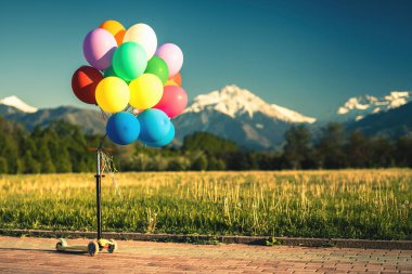 Çok renkli balonlar scooter açık Festivali mavi gökyüzü arka plan üzerinde tekme.