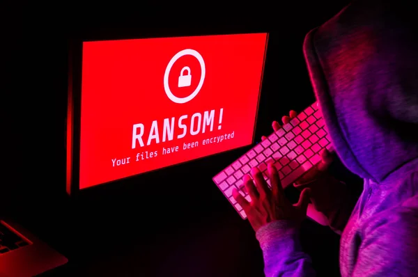 Tela do computador com alerta de ataque ransomware em vermelho e um hacker — Fotografia de Stock