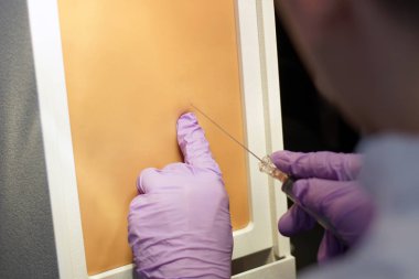 Eldiven ponksiyon için bir şırınga ile enjeksiyon yapma doktor. Simülasyon tıbbi eğitim modeli. Tıbbi müdahale kavramı, simülasyon tıp eğitimi.