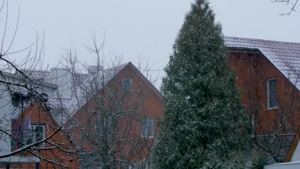 Nieve cae sobre el telón de fondo de las casas particulares — Vídeo de stock