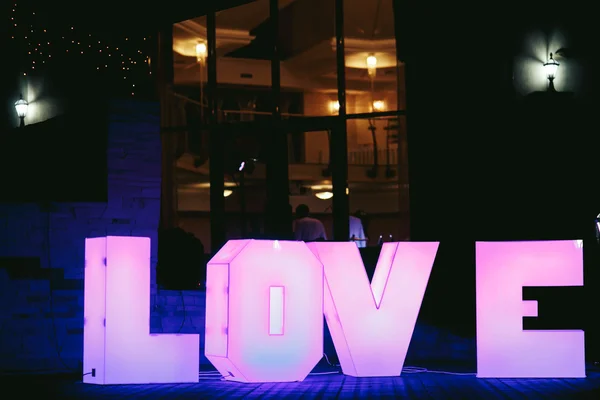 Iluminado grandes letras rosa AMOR antes do restaurante — Fotografia de Stock