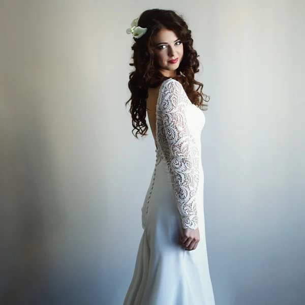 Bride with curly dark hair staying in full-length