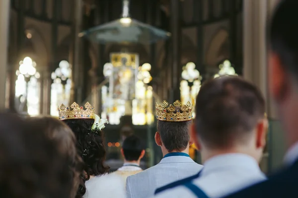 Fästman och bruden bär kronor under ceremonin i kyrka — Stockfoto