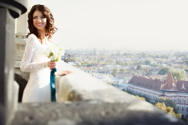 Noiva fica na varanda com grande paisagem urbana no backgrou — Fotografia de Stock