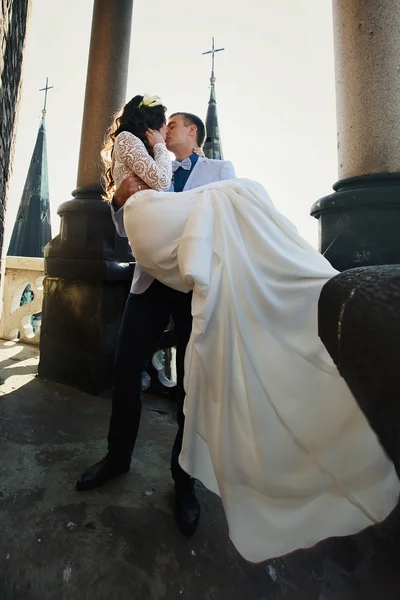 Noivo segura noiva em seus braços no telhado da velha catedral — Fotografia de Stock