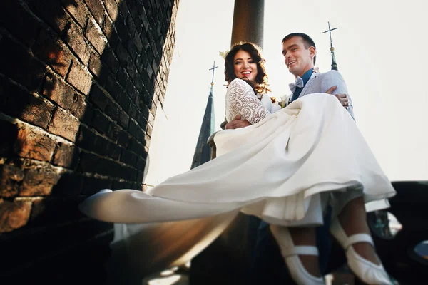 Noivo torcer noiva enquanto segurando-a em seus braços no telhado — Fotografia de Stock