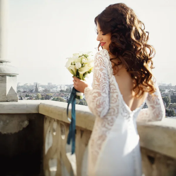 Noiva posa de volta com buquê de lírio com paisagem urbana no fundo — Fotografia de Stock