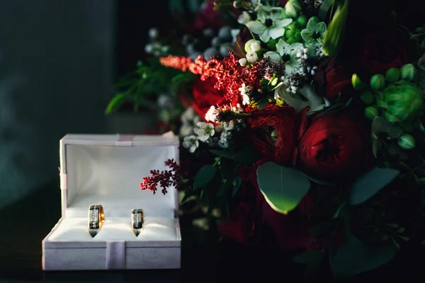 Anillos de boda y ramo en los rayos del sol — Foto de Stock