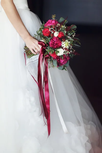 Невеста держит красный букет с лентами — стоковое фото