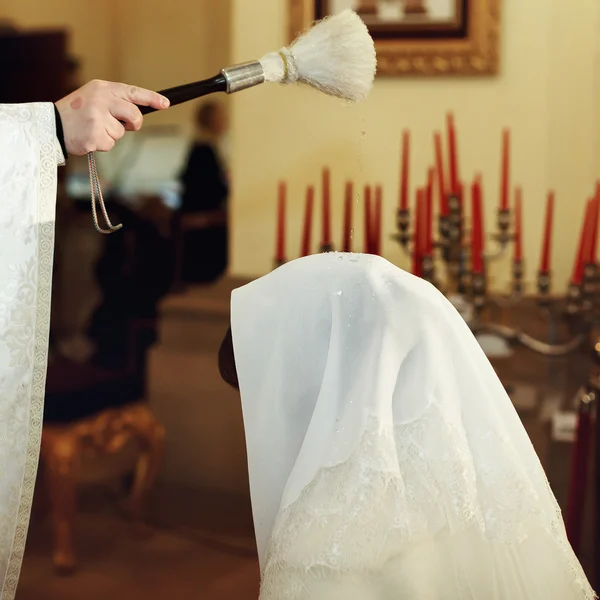 Prästen välsignar bruden medan hon står på knä i kyrkan — Stockfoto