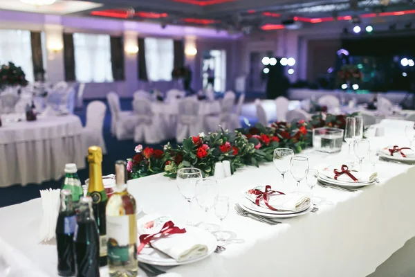 Hochzeitstisch üppig gedeckt und dekoriert mit roten Rosen und Grün — Stockfoto