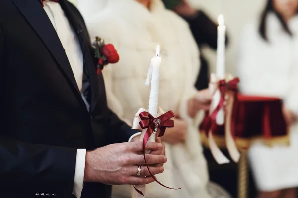 Новобрачные держат свечи во время молитвы в церкви — стоковое фото