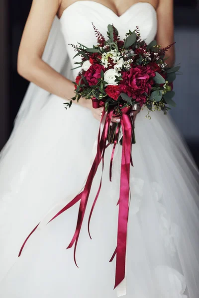 Sposa porta un bouquet rosso e bianco con nastri — Foto Stock