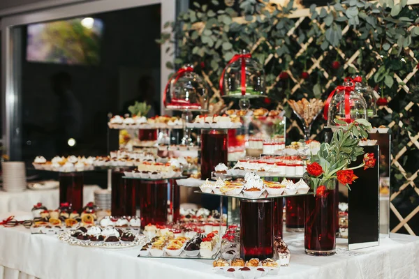 Cupcakes on the glass dishes put on a red vases — Stock Photo, Image