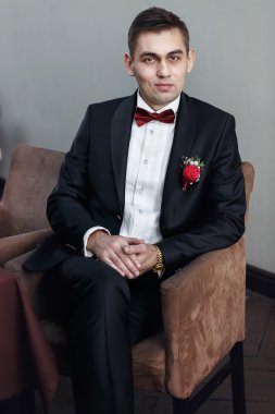 Damat smokin kahverengi sandalyede oturur