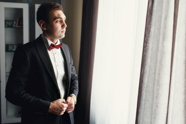 Şık siyah elbiseli adam pencereden ciddi görünüyor