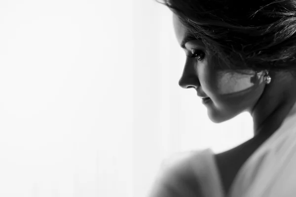 Bride looks over her shoulder in the light of the window — Stock Photo, Image