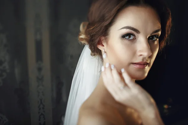 Nevěsta v závoji dotkne její tváře s rukou — Stock fotografie