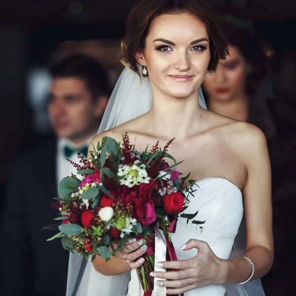 Mariée souriante tient un bouquet rouge — Photo