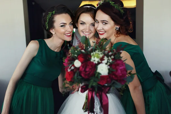 Bride poses with bridesmaids reaching out her hand with bouquet — Stock Photo, Image