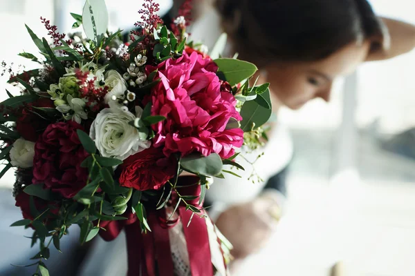 Mariée tendre la main avec un bouquet décoré de rouge et blanc — Photo