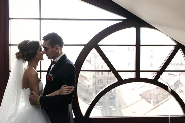 Yeni evliler sarılmak panoramik pencere önünde — Stok fotoğraf