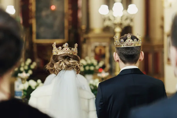 Blick auf den Rücken von Frischvermählten in Kronen aus der Menge in der Kirche — Stockfoto