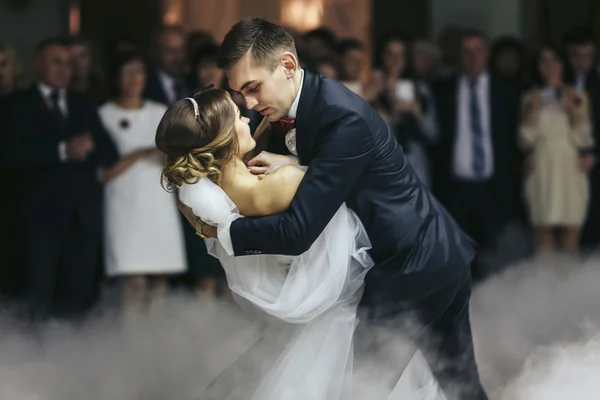 Verloofde houdt bruid in zijn handen tijdens het dansen in de rook — Stockfoto