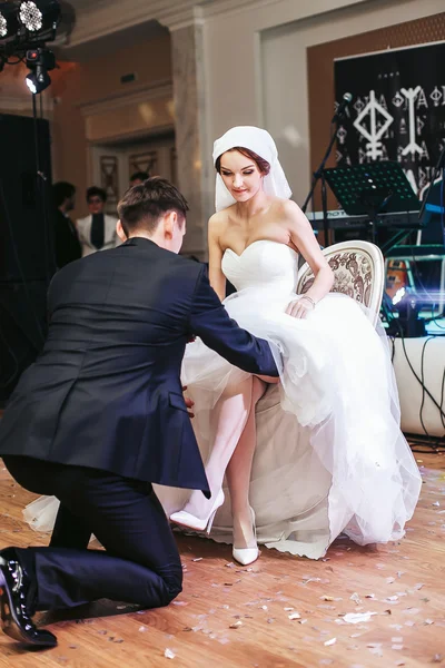 Fiance repousse une jarretière de la jambe de la mariée — Photo