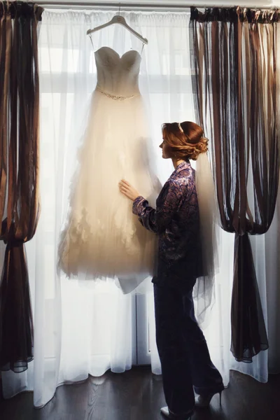 Невеста касается свадебного платья, прежде чем надеть его — стоковое фото