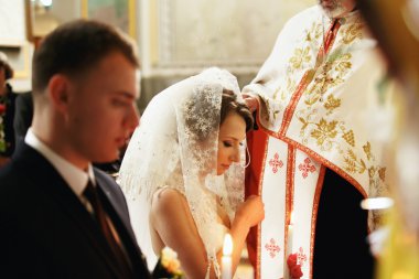 Bir rahip önce diz gelin peçe içinde duruyor