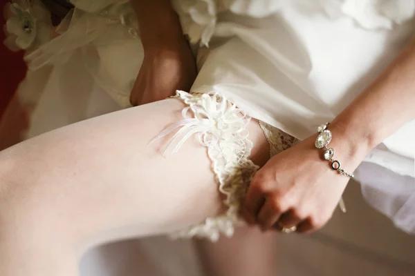 La sposa aggiusta una giarrettiera di laccio su una calza — Foto Stock