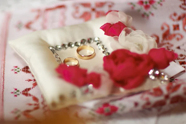 Anillos de boda se encuentran en la almohada con cristales y rosa de seda — Foto de Stock