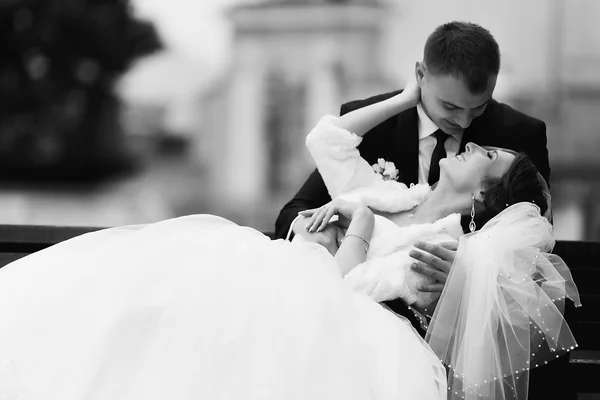 Sposa poggia sulle ginocchia dello sposo da qualche parte sulla panchina — Foto Stock