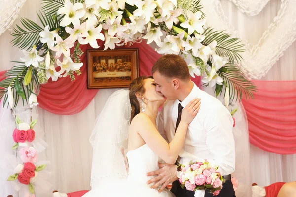 Frisch verheirateter Kuss vor dem Altar aus Lilien — Stockfoto