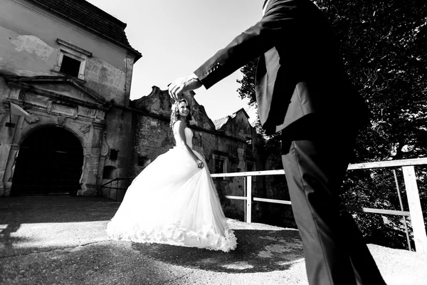 Жених достигает невесты, пока она поворачивается — стоковое фото